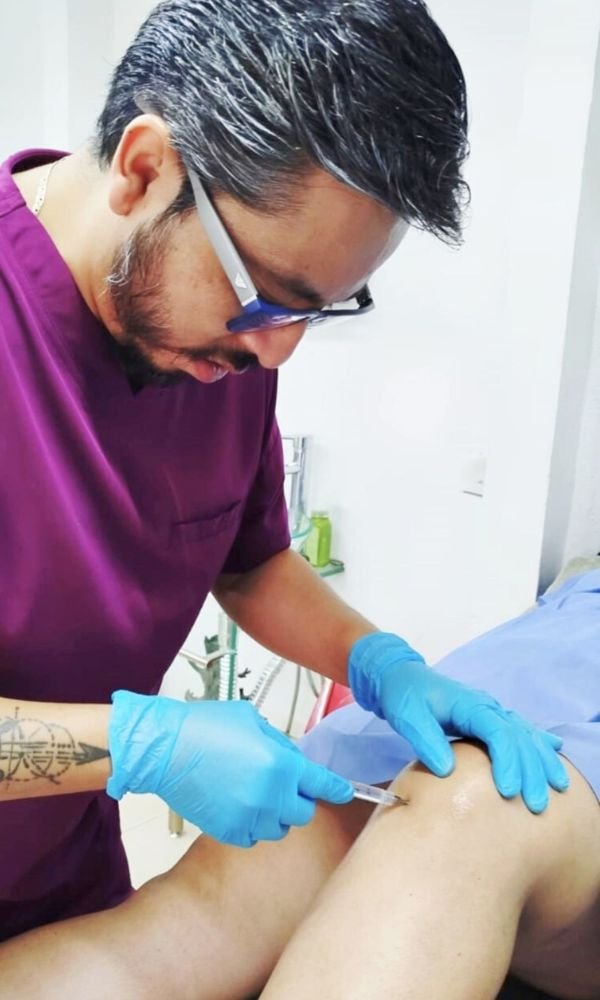 Médico especialista en rodilla administra una inyección médica en la rodilla de un paciente.